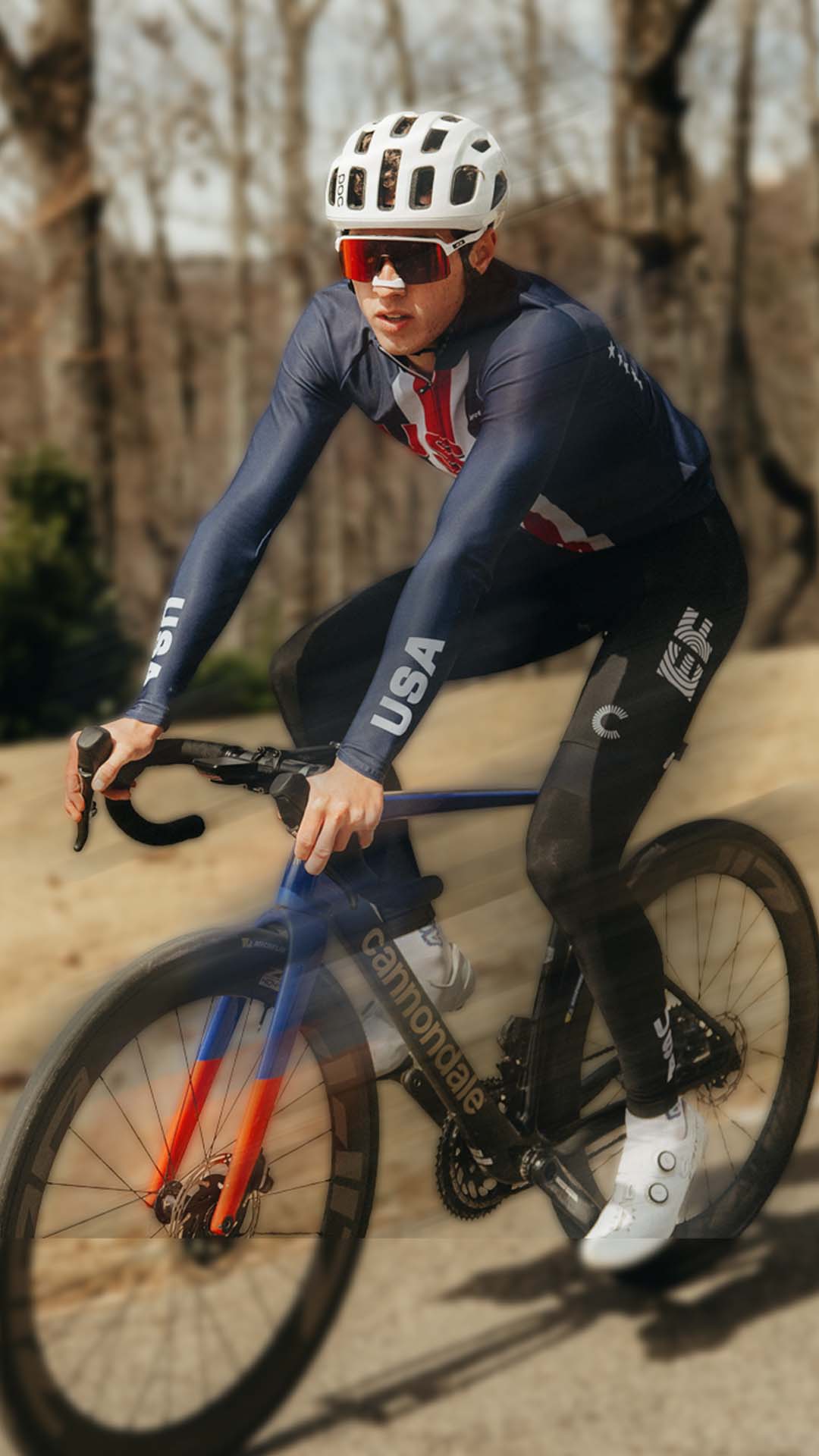 Cyclist in a racing suit riding a bicycle on a road with trees in the background